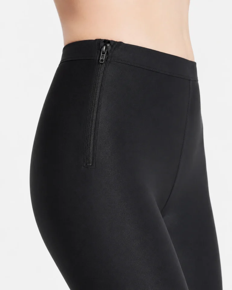 Black compression leggings close-up showing the side zipper and waistband seams