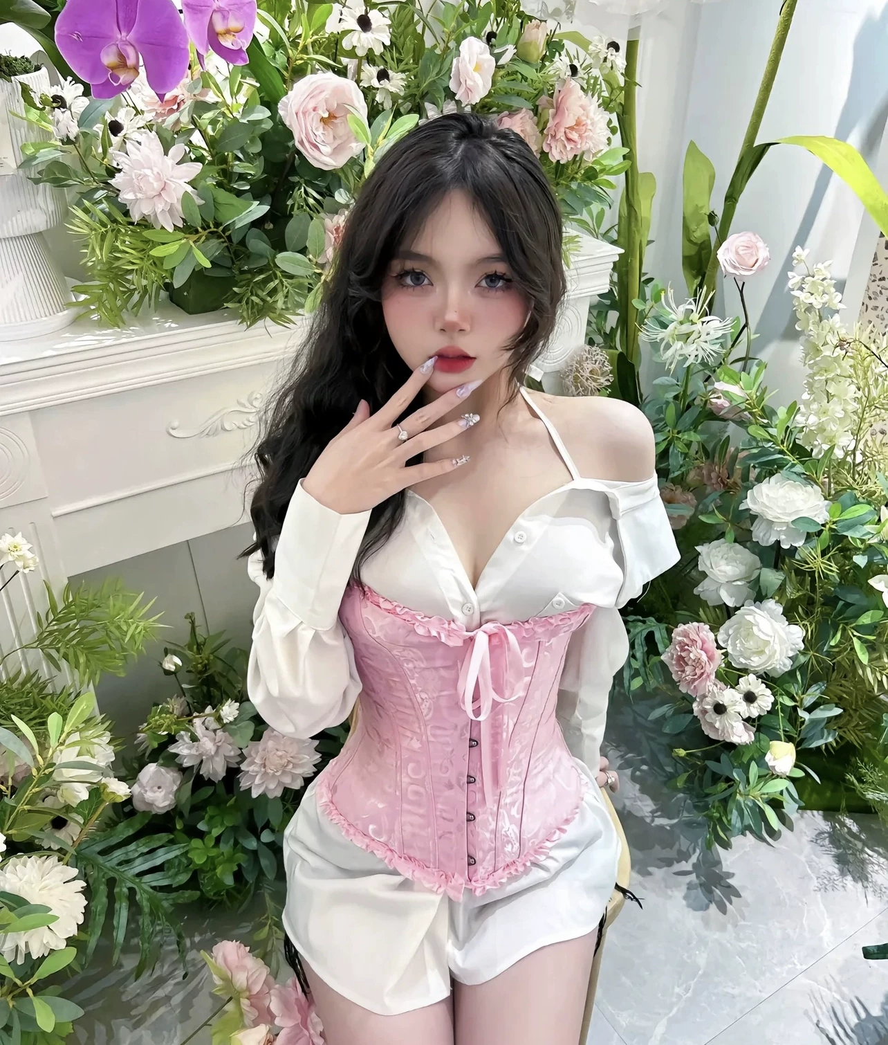Pink strapless corset styled over a white blouse in a floral setting