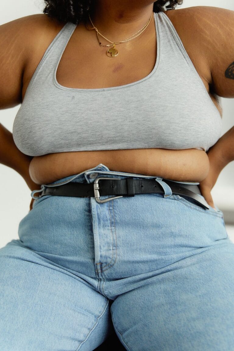 Close-up of a plus-size woman in denim jeans for checking waistband interaction with shapewear