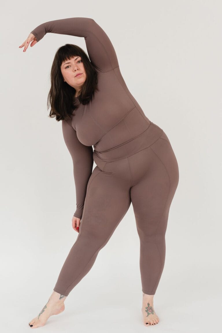 Plus-size woman stretching in a studio to illustrate movement testing for shapewear fit